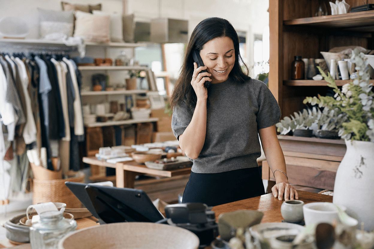 A retail shop owner returns a customer's call on a smartphone shortly after receiving a new lead, illustrating fast follow-up.